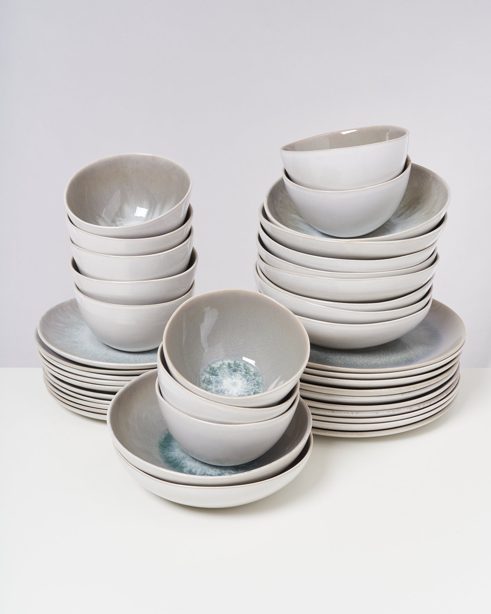 Ein Stapel aus Porzellanschalen und Tellern auf einem weißen Tisch vor einem neutralen Hintergrund.