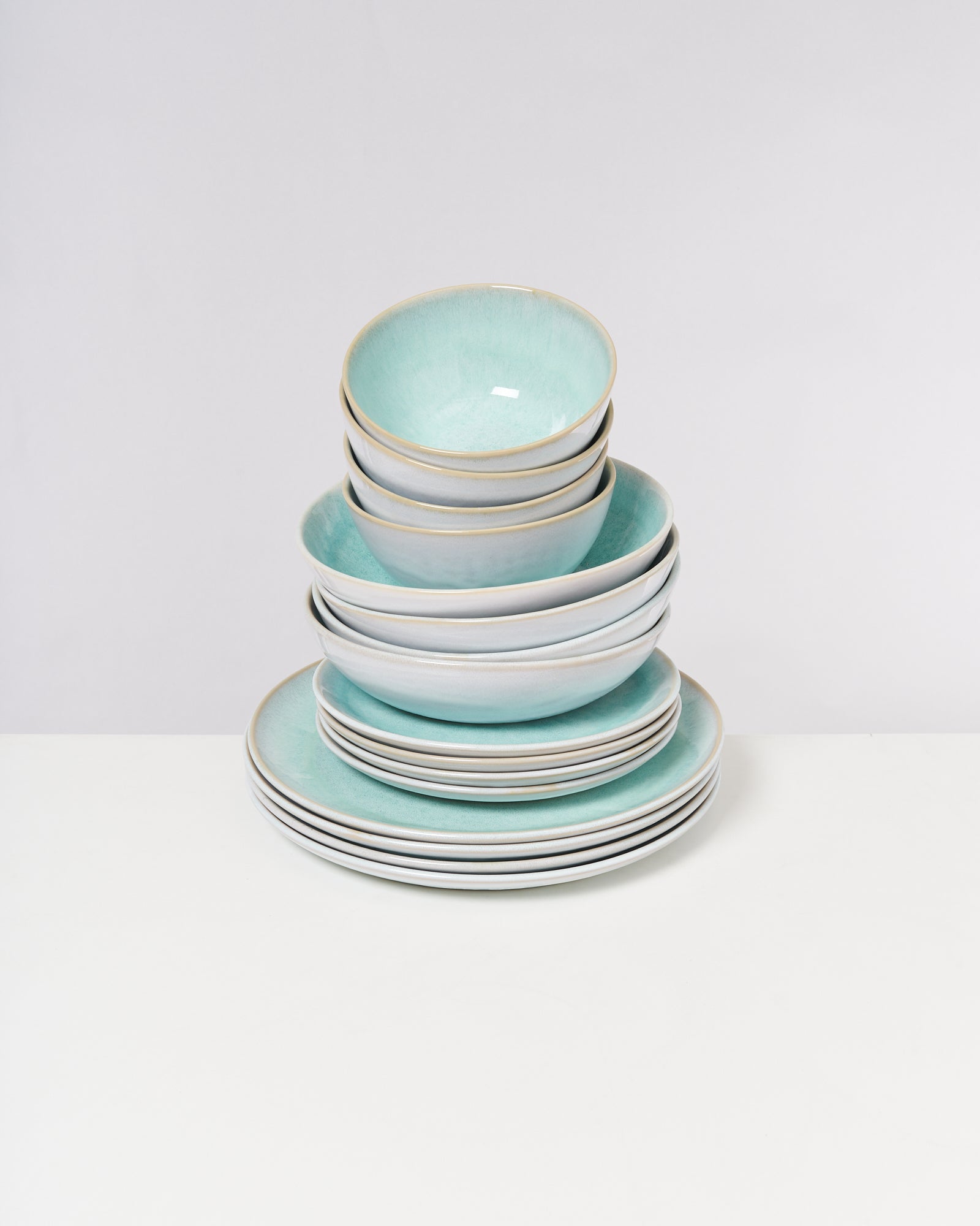 Ein Stapel aus stilvoll gestapelten blauen und weißen Schüsseln und Tellern auf weißem Hintergrund.