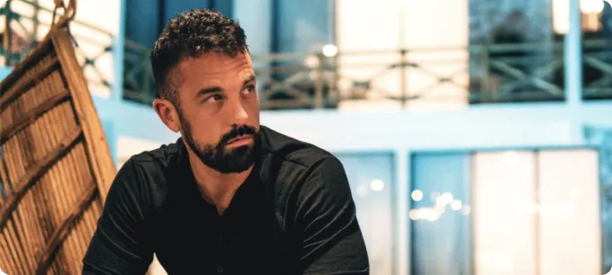 A sitting bearded middle-aged man in a black shirt.